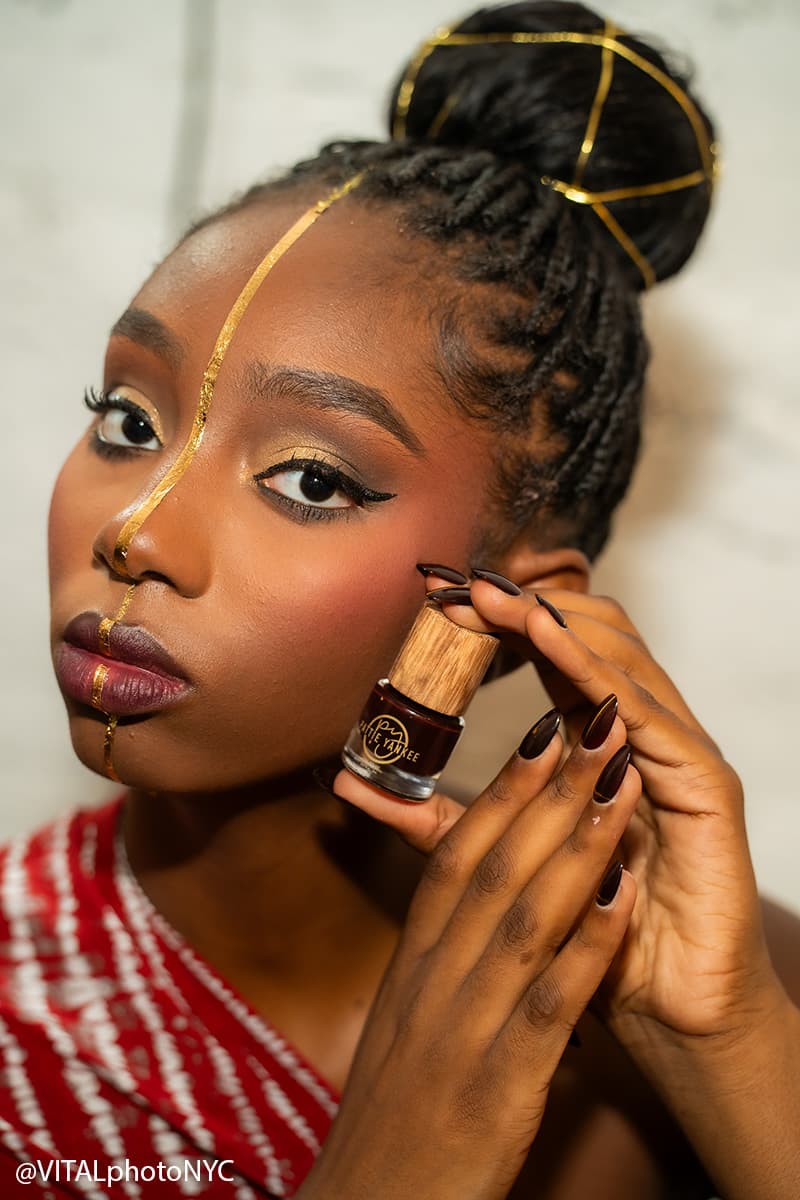 A model backstage with a gold line painted down the centre of her face and gold thread in her hair