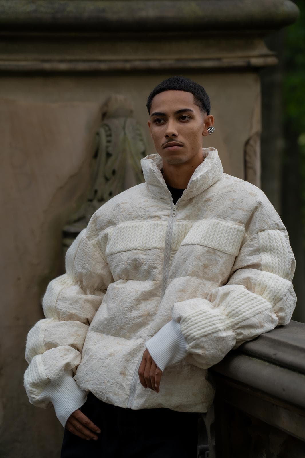 The House of Nova Stream Coat, a white down puffer with knit panels and a funnel neck, photographed against carved stone