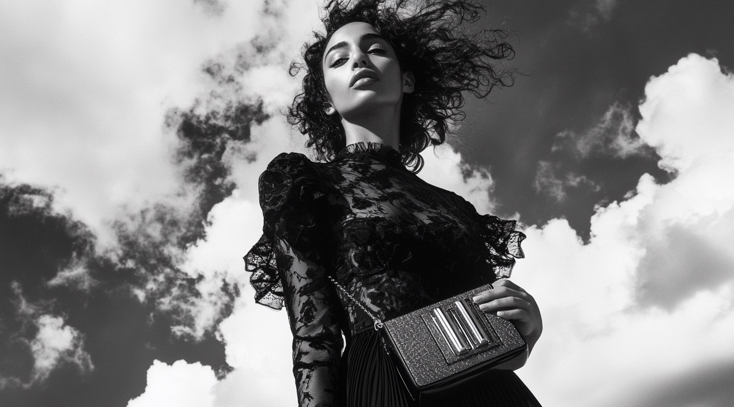 Black lace and a glitter clutch photographed from below against cloud